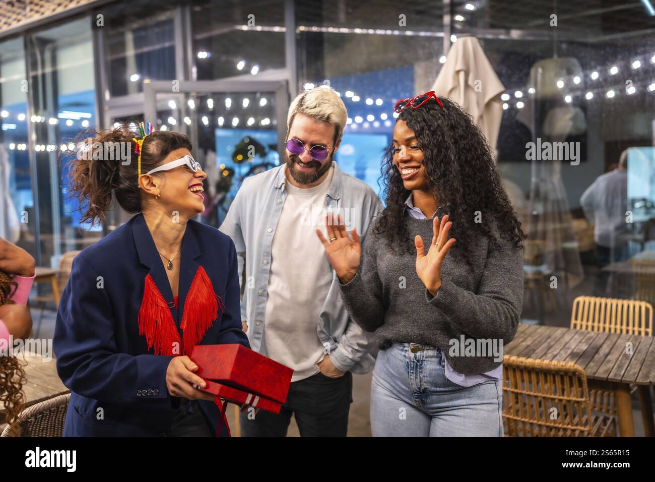 Happy woman receiving birthday gift during night party with friends in a bar Stock Photo