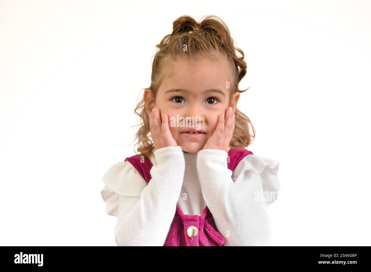 Studio portrait of a surprised little girl holding her cheeks with her ...