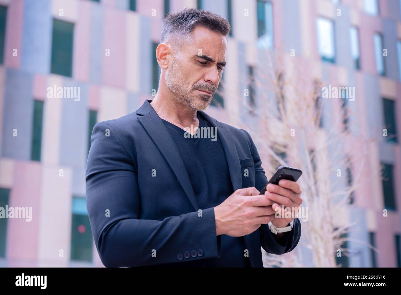 Confident businessman using smartphone outdoors, Stock Photo