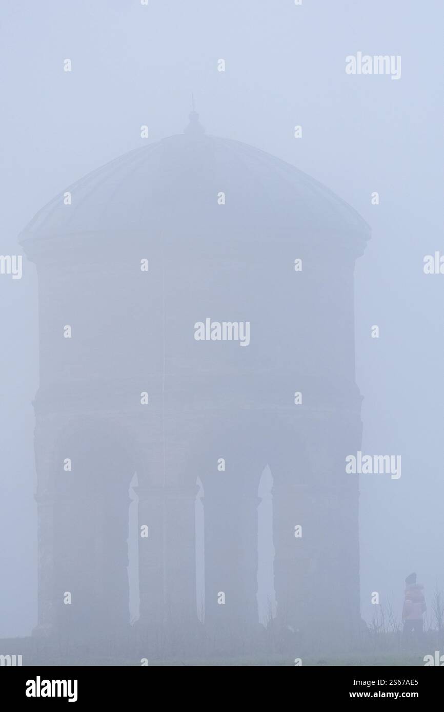 A person walks by Chesterton Windmill during heavy fog in Chesterton in Warwickshire. A yellow alert for fog has come into force, with the Met Office warning the weather could cause travel disruption including flight delays or cancellations. Picture date: Thursday January 16, 2025. Stock Photo