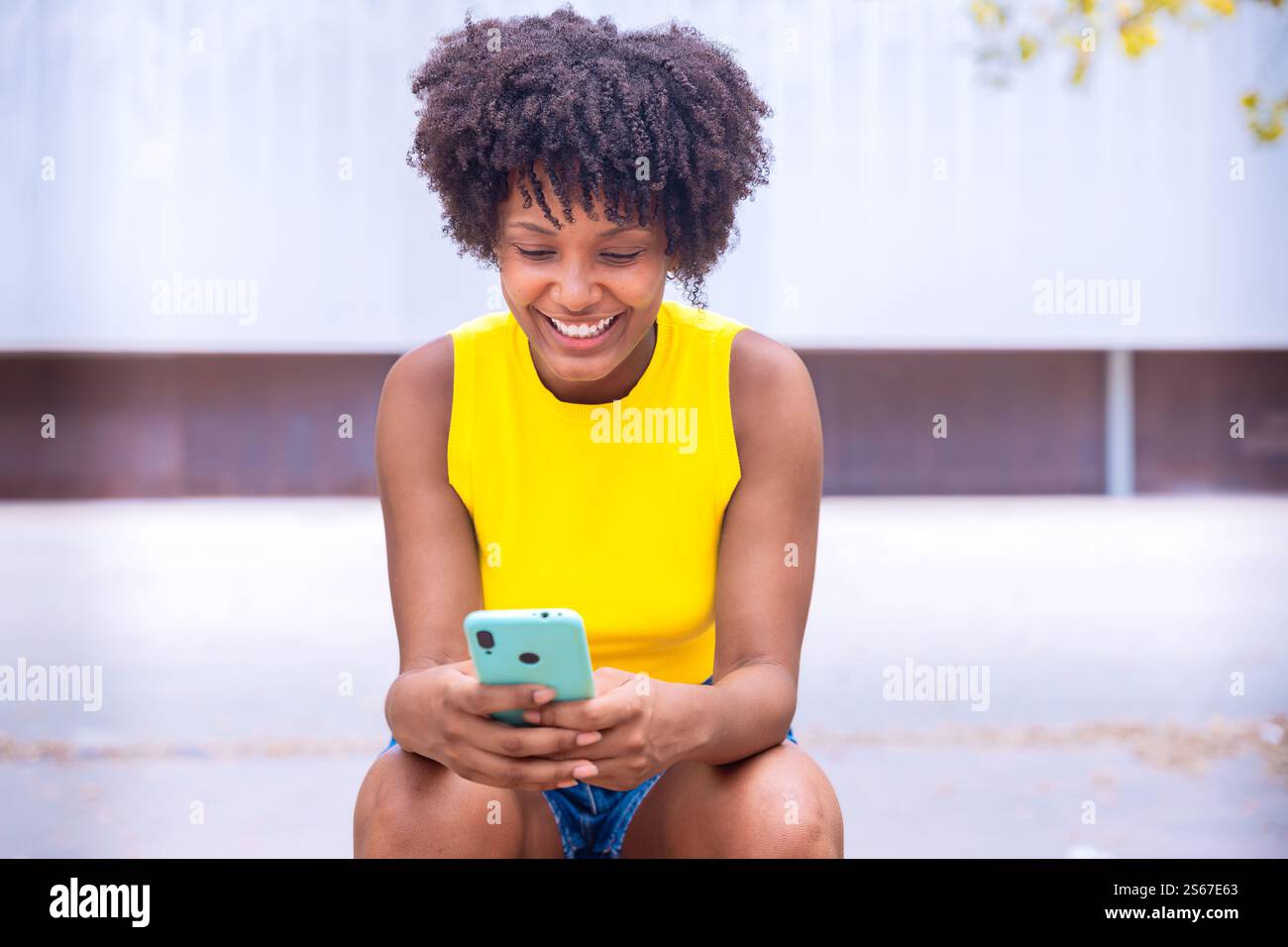 Smiling african american Young Woman Holding Smartphone Outdoors Stock Photo
