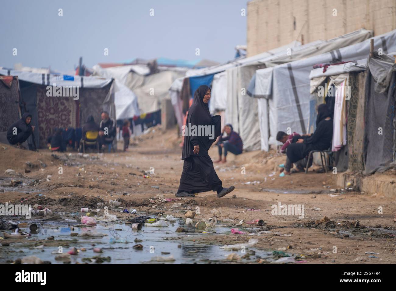 A woman walk at a tent camp for displaced Palestinians in Deir al-Balah ...