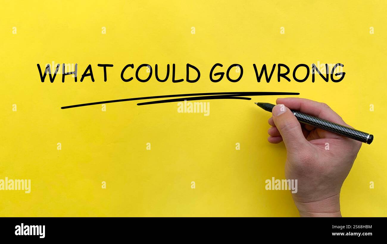 Hand writing What Could Go Wrong text on yellow cover board Stock Photo