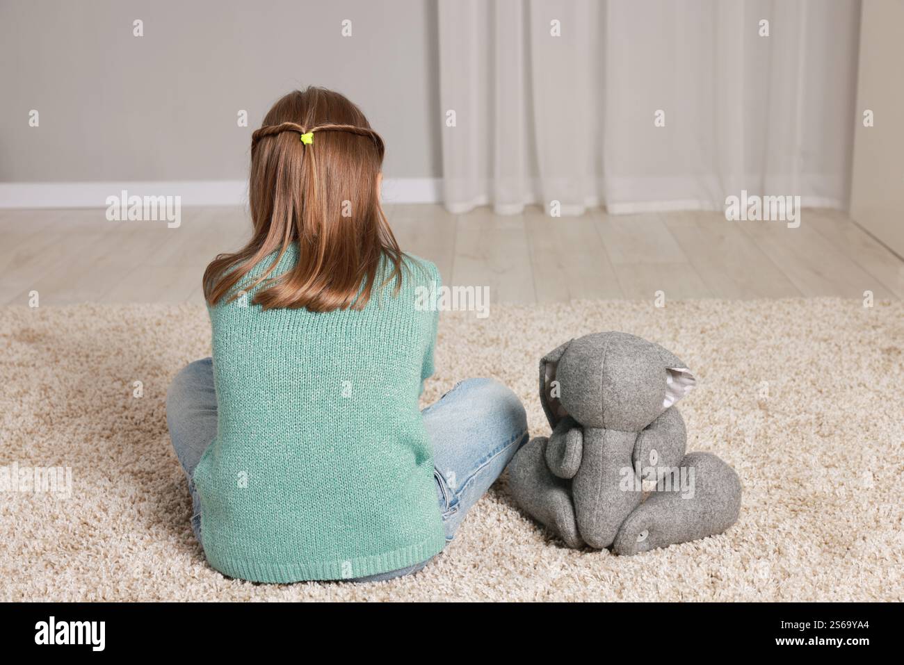 Autism concept. Lonely little girl with toy bunny on floor at home ...