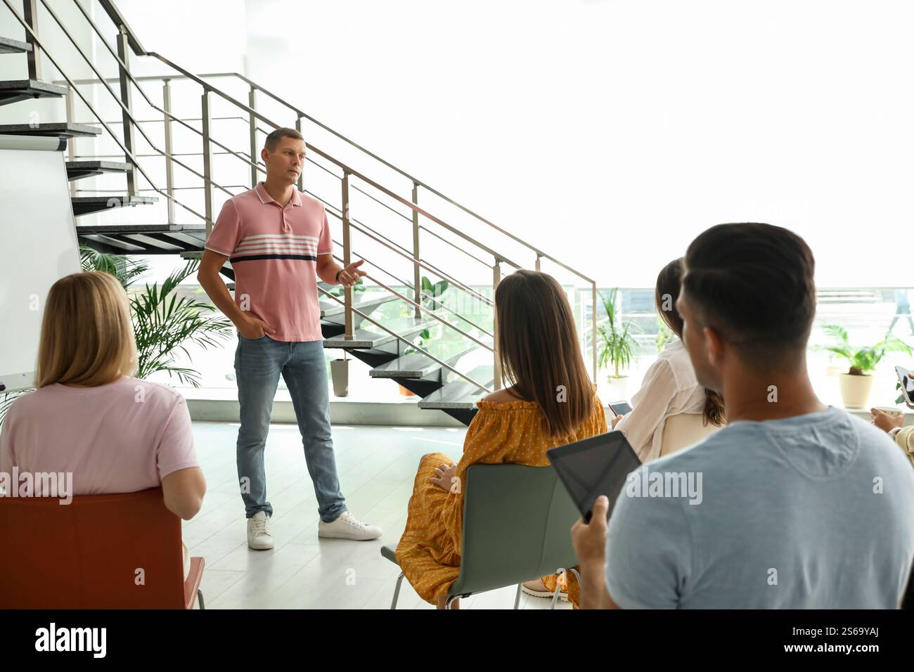Male lecturer in casual clothes talking to audience indoors Stock Photo