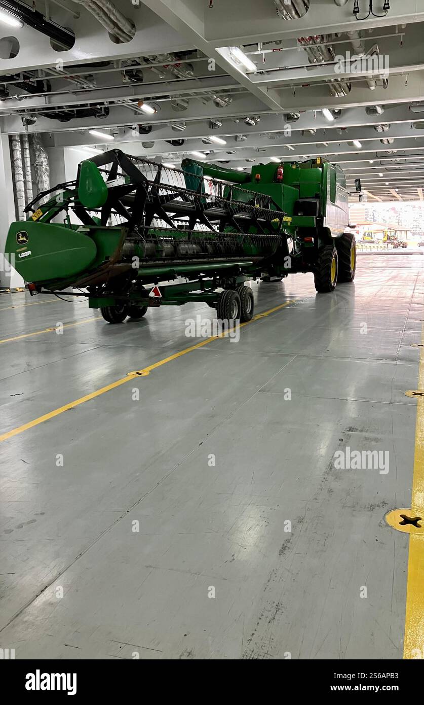 Farm Equipment and Machinery: Green Harvester on a Ferry Vehicle Deck - Smartphone Captured Stock Image