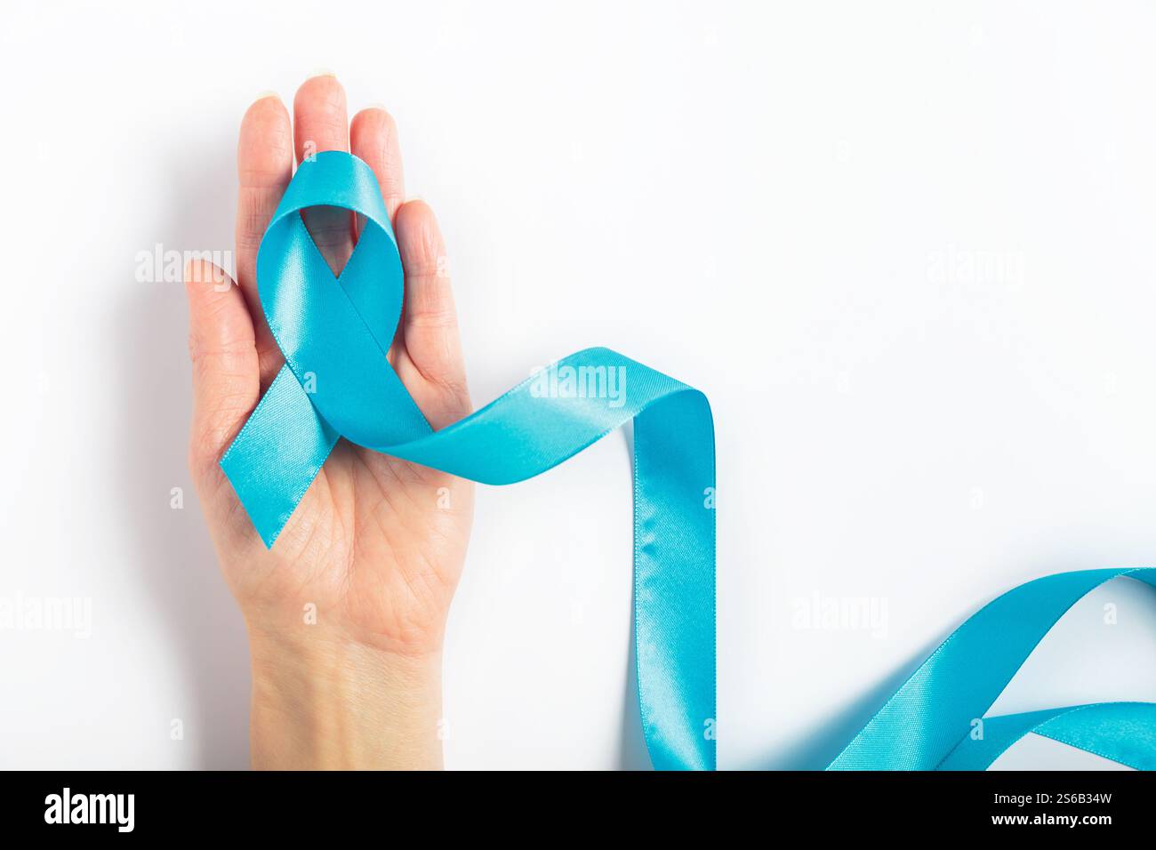 Colorectal cancer ribbon in womans hand on blue surface Stock Photo - Alamy