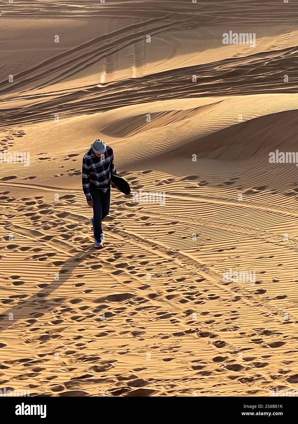 Elderly man walking with sandboard under arm up sand dune - Smartphone Captured Stock Image