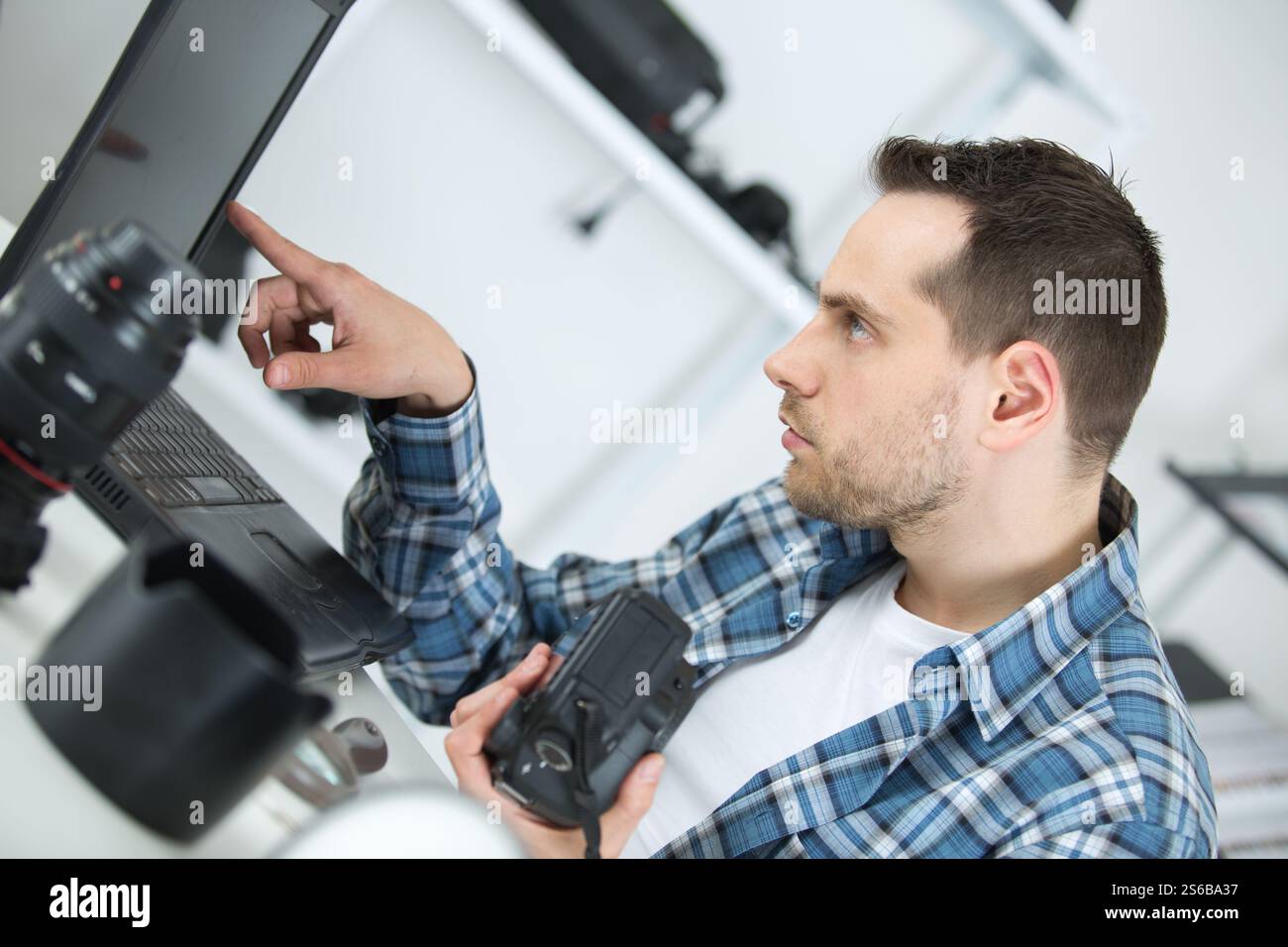 camera repairman looking at laptop Stock Photo