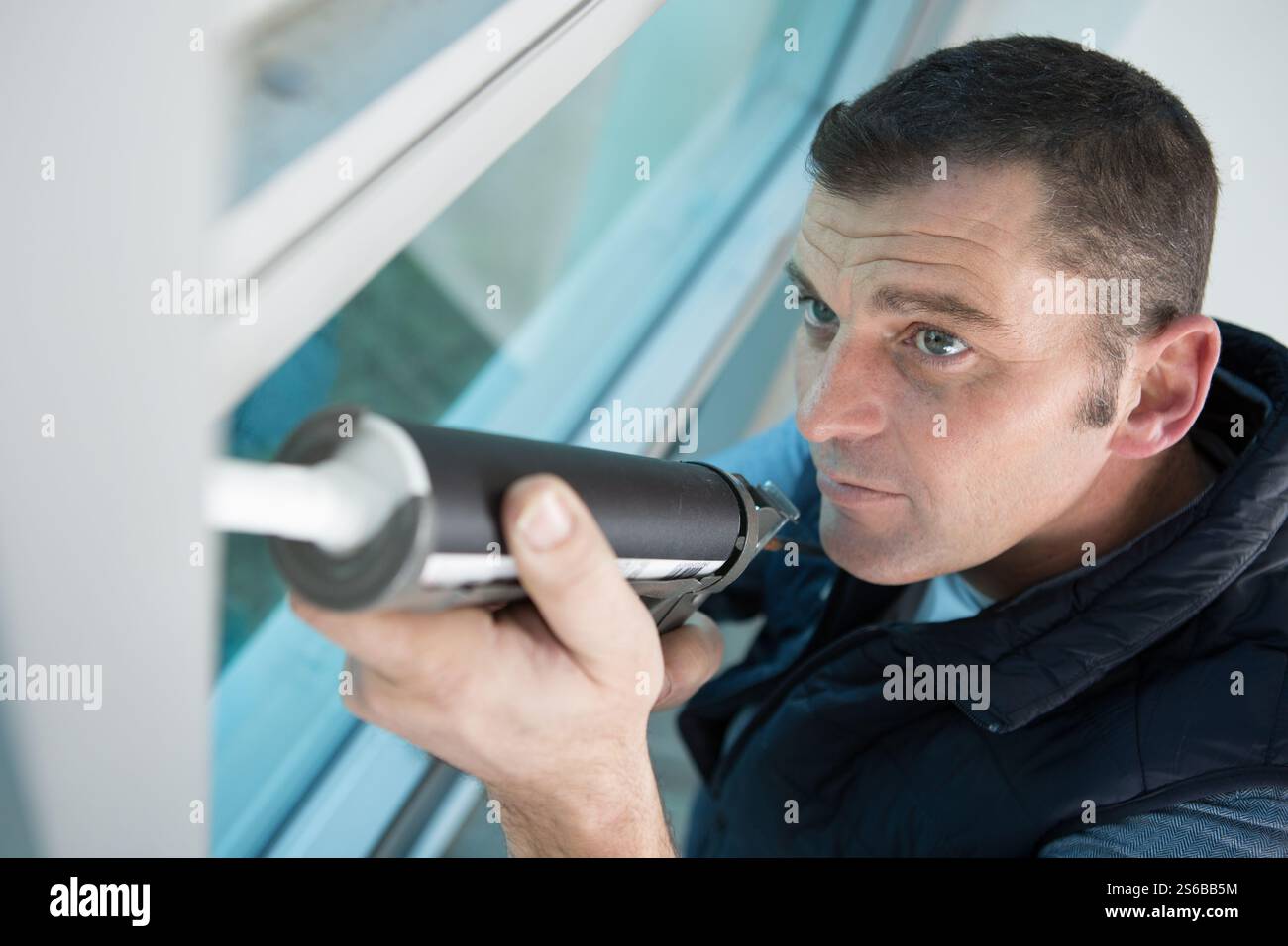 construction worker using caulk gun on window Stock Photo