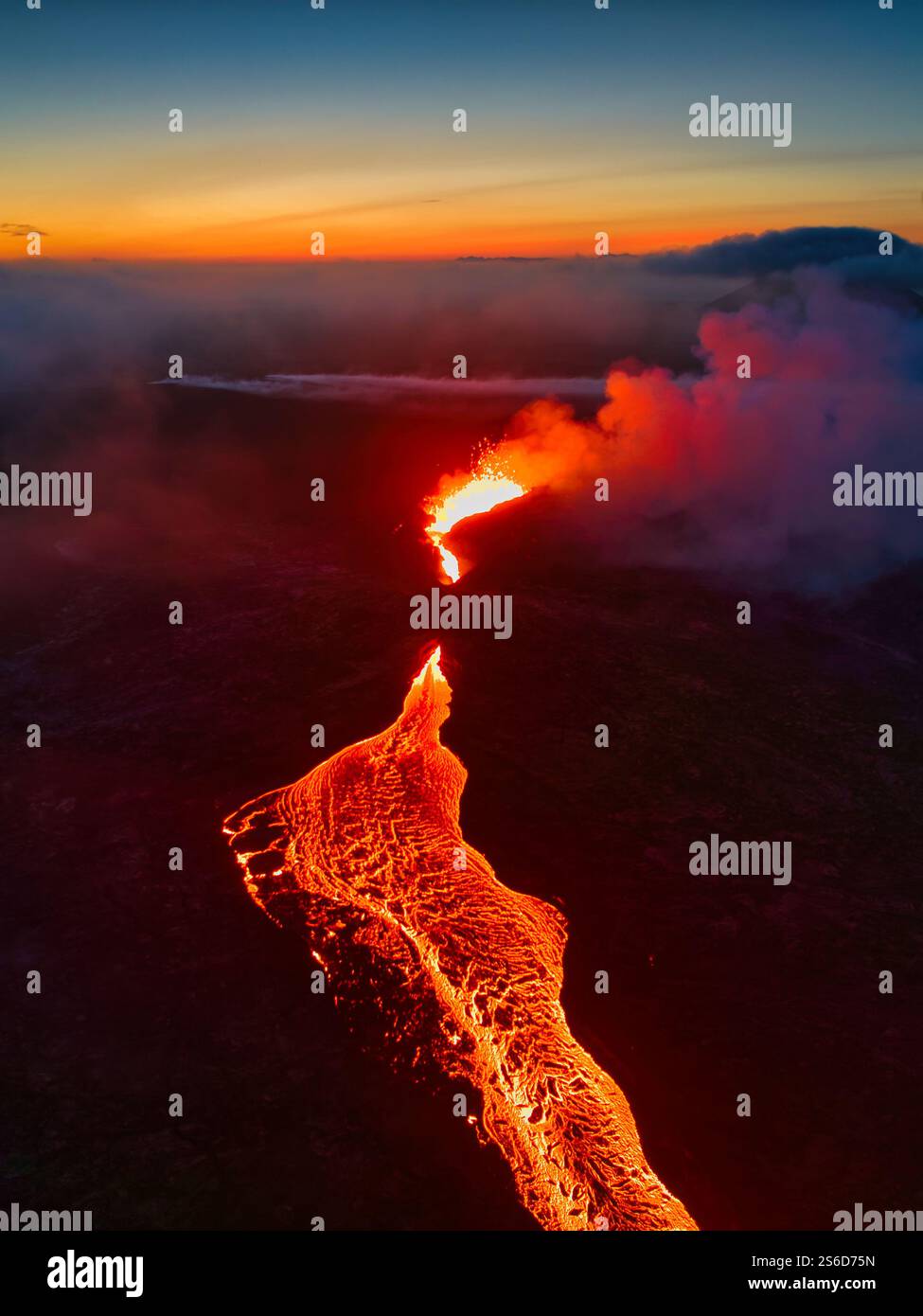 Aerial view of a volcanic eruption in Iceland at sunset, with glowing lava rivers and vibrant skies creating a dramatic natural spectacle Stock Photo