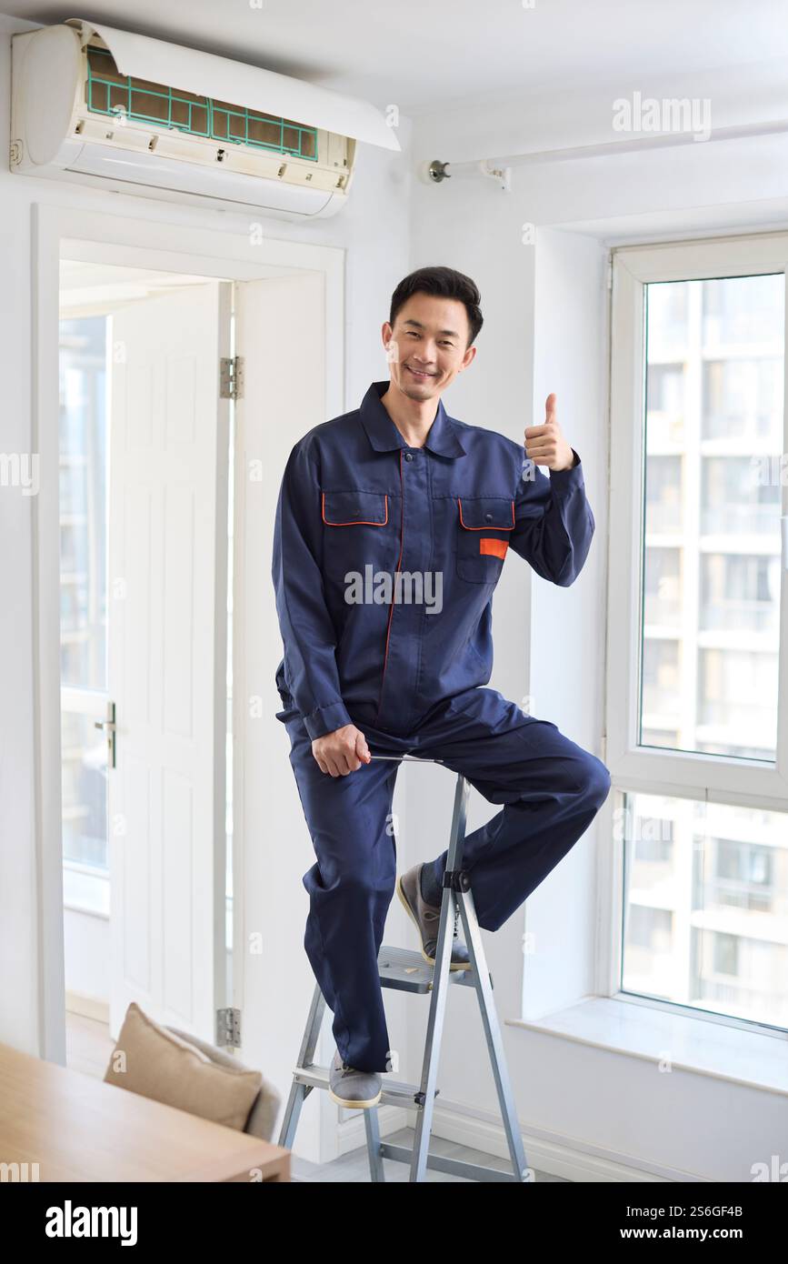 Handyman fixing the air conditioner Stock Photo