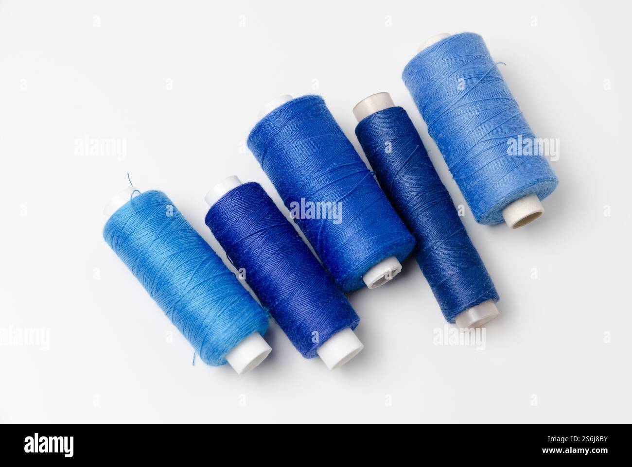Blue thread spools on white background Stock Photo - Alamy