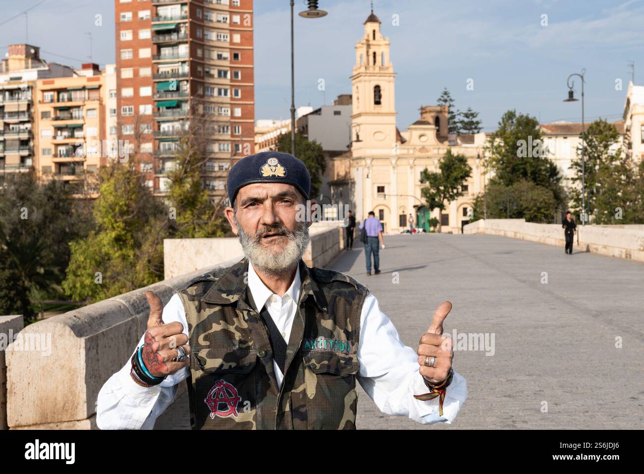 Old bearded man in military clothes looking at camera showing thumbs up. Hard life vulnerable people concept. Valencia, Spain Stock Photo