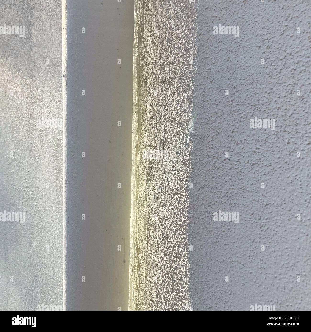 A detailed view of a building corner showcasing two contrasting wall textures, one smooth and the other rough, illuminated by natural daylight. - Smartphone Captured Stock Image