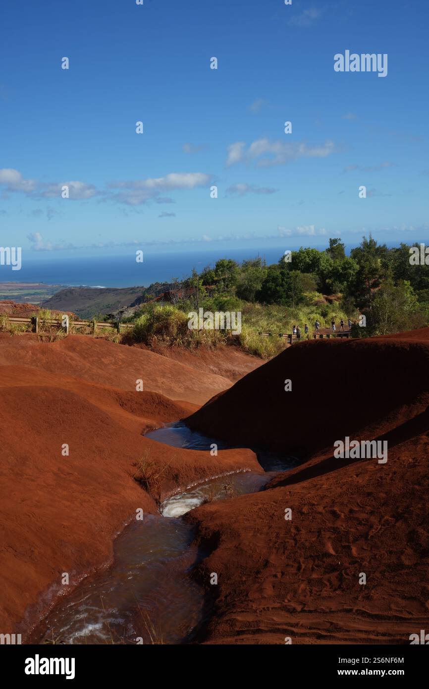Red Dirt Falls on Kauai, Hawaii, featuring vibrant red sand formations and a small cascading stream, showcasing the island's unique geological beauty. Stock Photo
