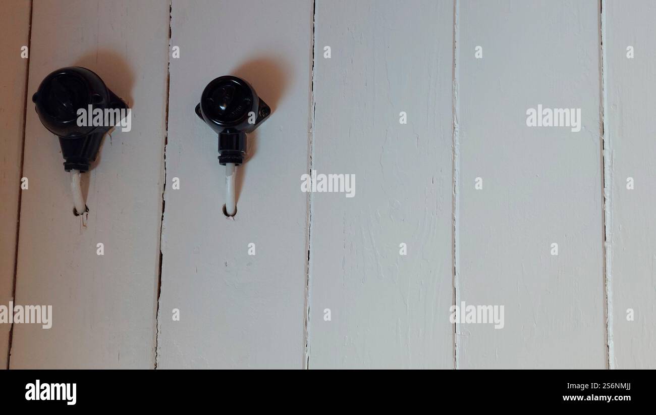 Black Bakelite rotary switch on white painted wooden wall Stock Photo
