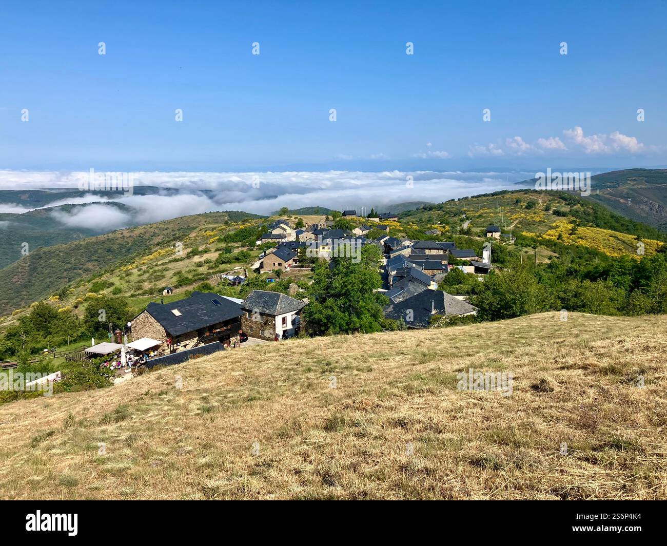 View of the ancient Spanish mountain village of El Acebo on the Camino de Frances, descending from Cruz de Fierro to Molineseca. Mist and fog below. - Smartphone Captured Stock Image
