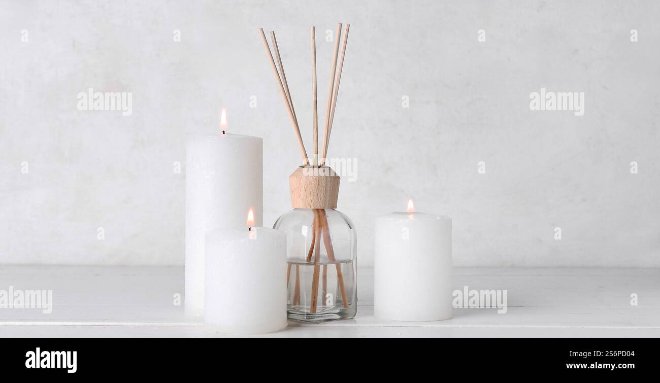 Burning candles and reed diffuser on white background Stock Photo