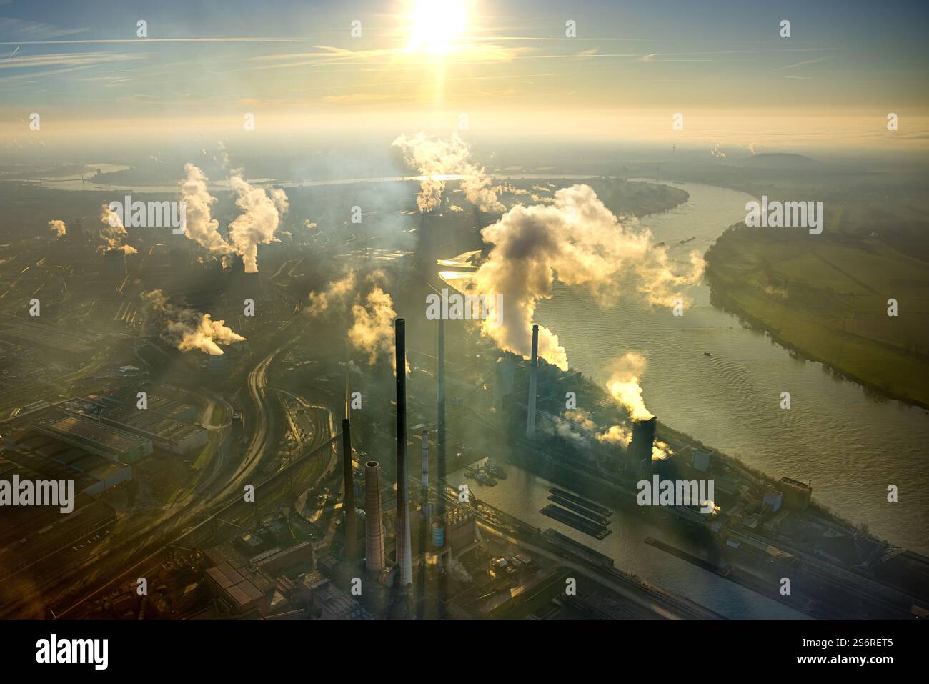 Luftbild, Thyssen Krupp Steel Europe AG am Fluss Rhein, Werkshafen Schwelgern, Gegenlicht und strahlenförmige Sonne am blauen Himmel, qualmende rauche Stock Photo