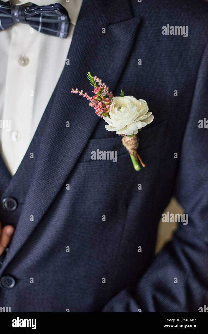 Elegant groom in navy suit with white boutonniere, floral decoration on ...