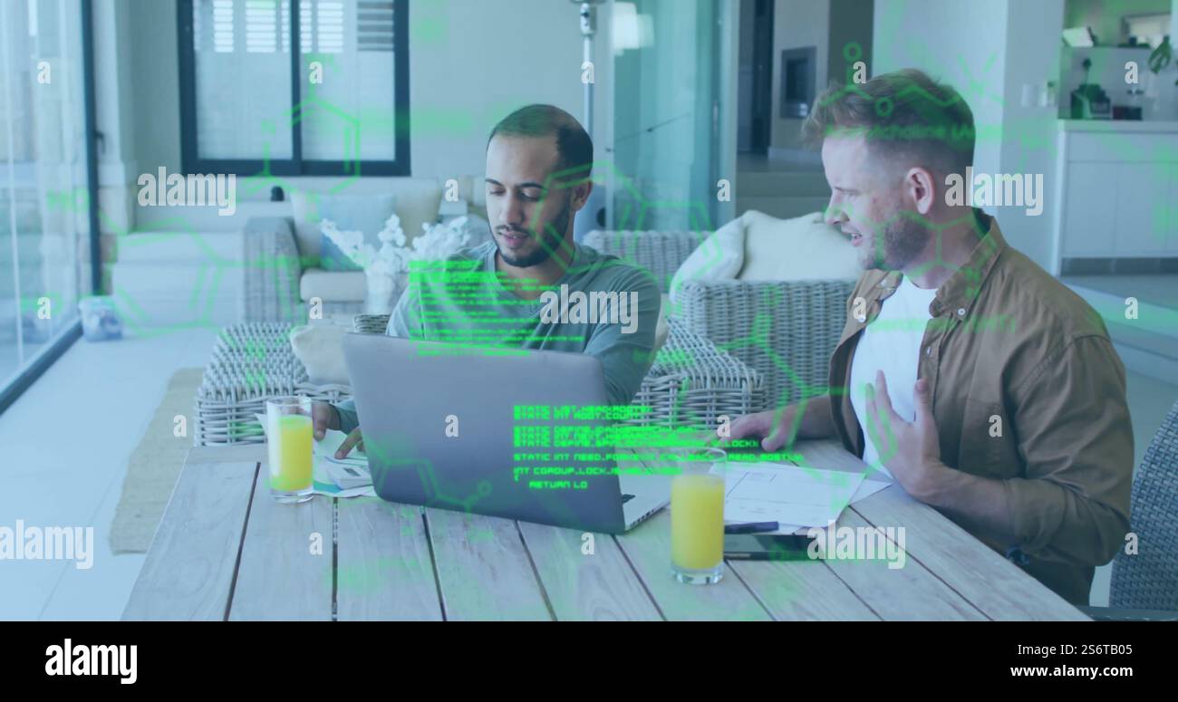 Green digital data image over two men working on laptops at table Stock Photo