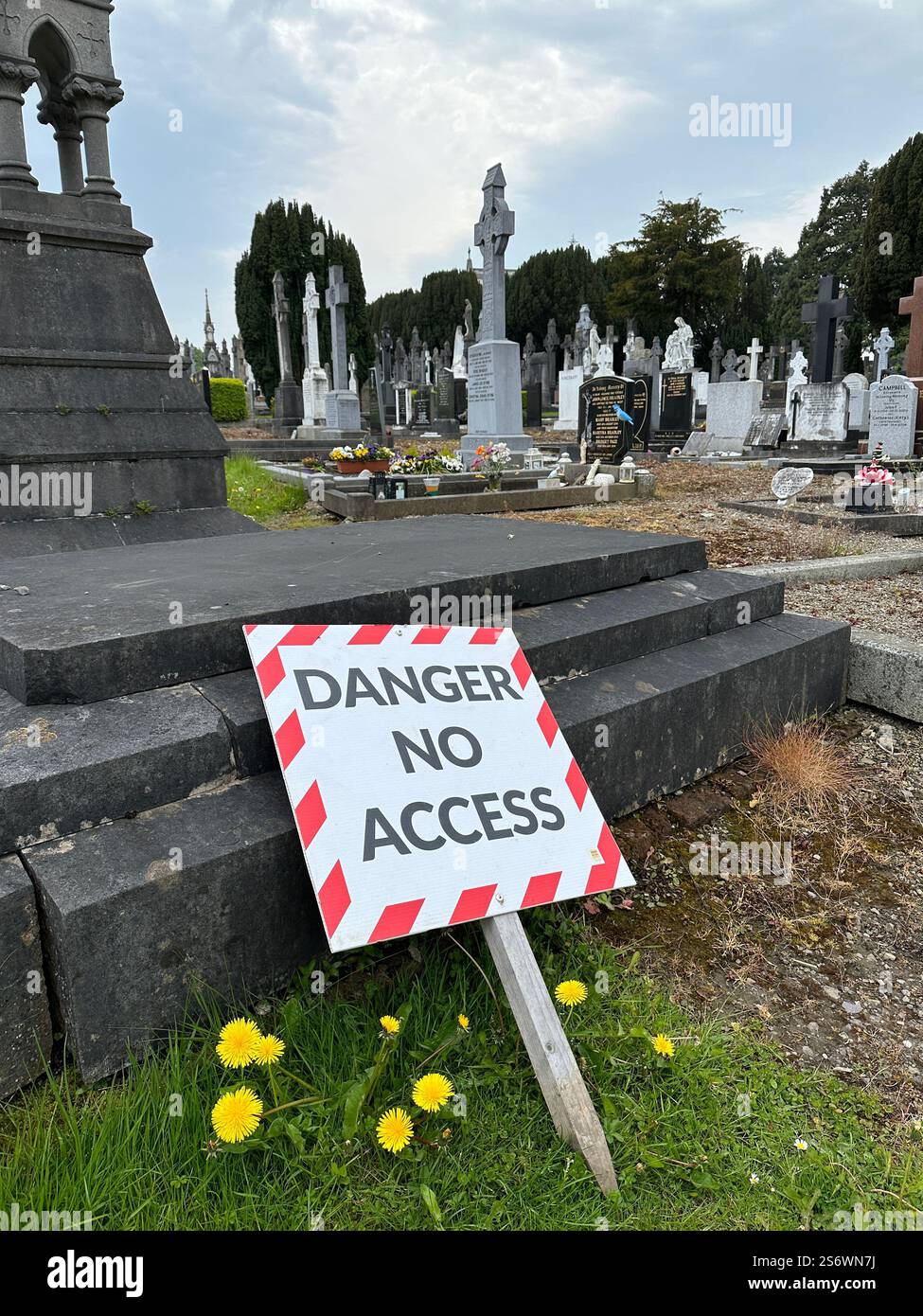 A sign reading "Danger No Access" leaning against a grave at Glasnevin Cemetery in Dublin, Ireland. - Smartphone Captured Stock Image