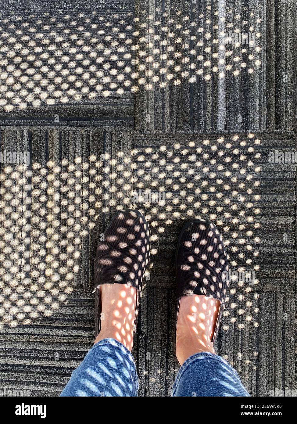 Geometric patterns falling across a carpet and a woman's feet. - Smartphone Captured Stock Image