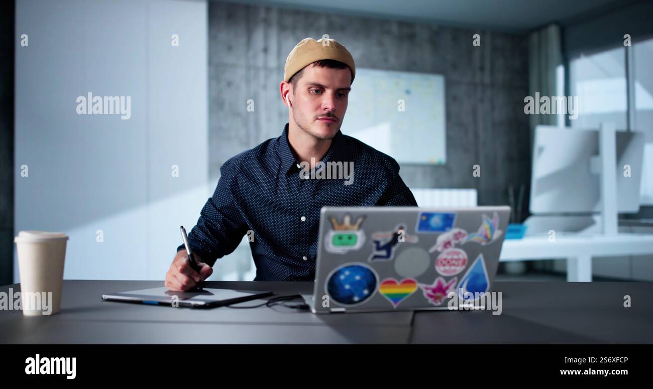 Happy Young Male Designer Using Laptop In Office Stock Photo