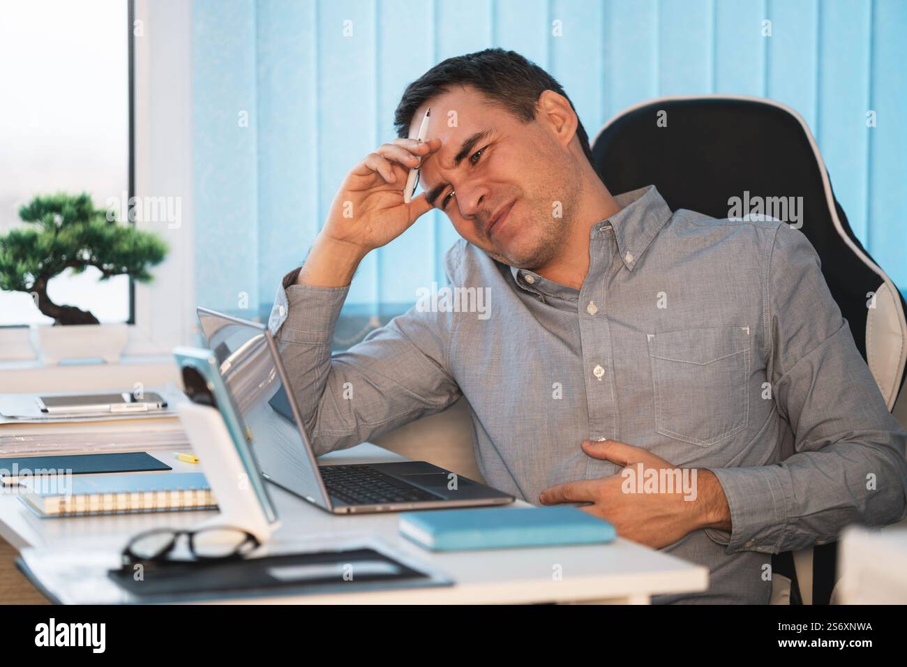 businessman having a stomachache. the concept of hunger at work, rumbling in the stomach, a sick employee. Stock Photo