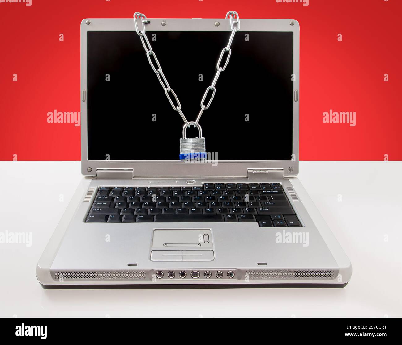 Laptop protected using a steel chain and padlock, symbolizing security and data protection. Stock Photo