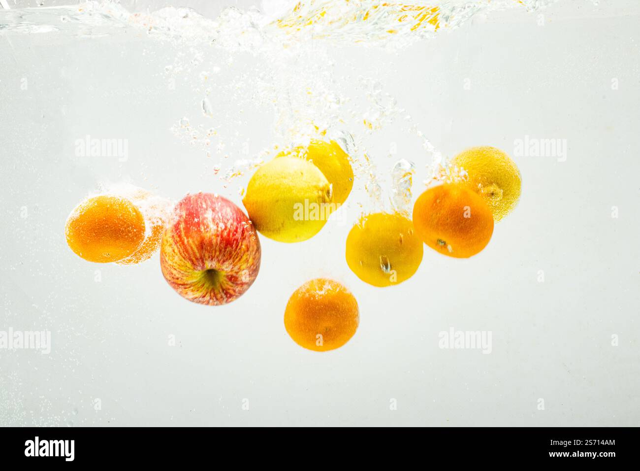 Fruit dropping into water. Healthy eating with oranges, apples, and lemons.  - Stock Image