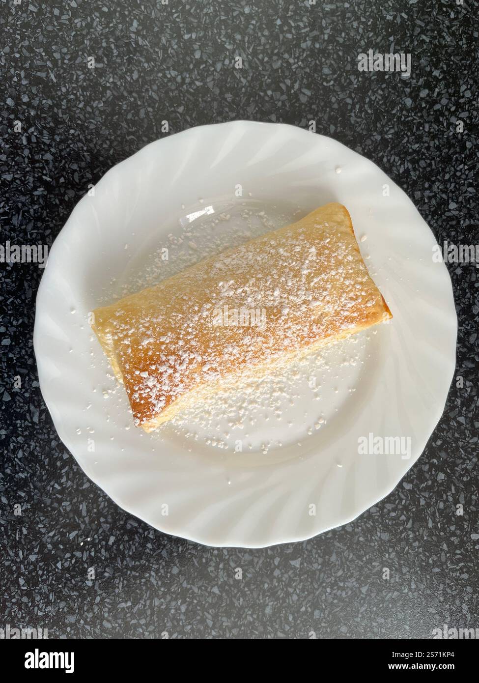 homemade apple turnover, puff pastry and cinnamon applesauce on a white plate on a black tabletop - Smartphone Captured Stock Image