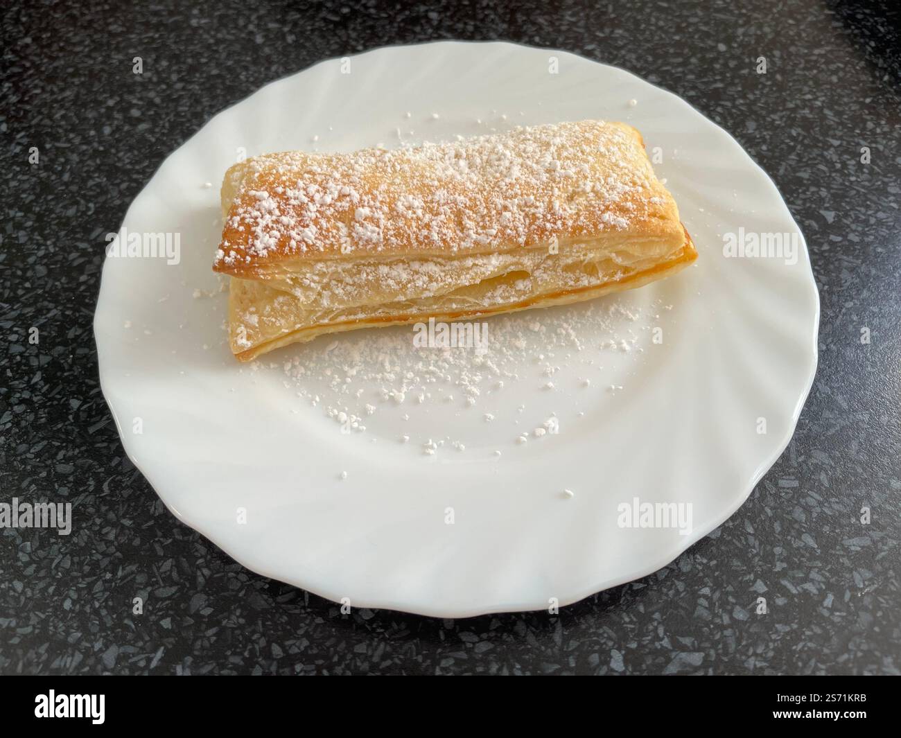 homemade apple turnover, puff pastry and cinnamon applesauce on a white plate on a black tabletop - Smartphone Captured Stock Image