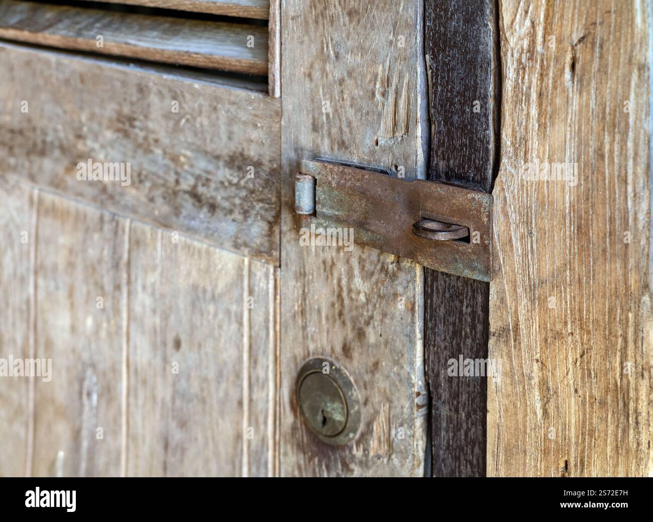 Old rusty metal security Padlock Hasp and keyhole on brown old aged wooden door without lock. Stock Photo