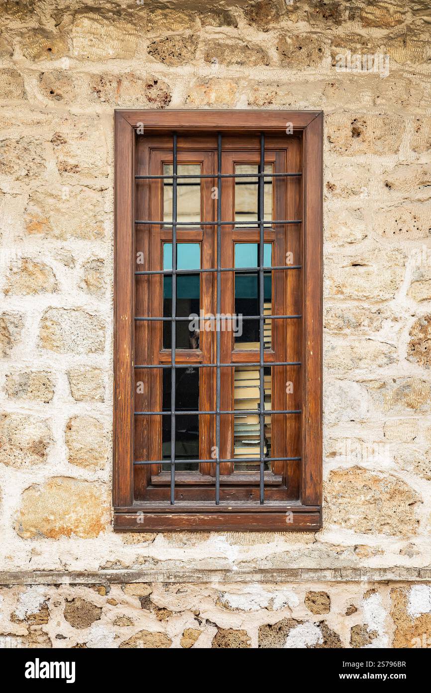 Rustic wooden window with bars on stone wall. Stock Photo