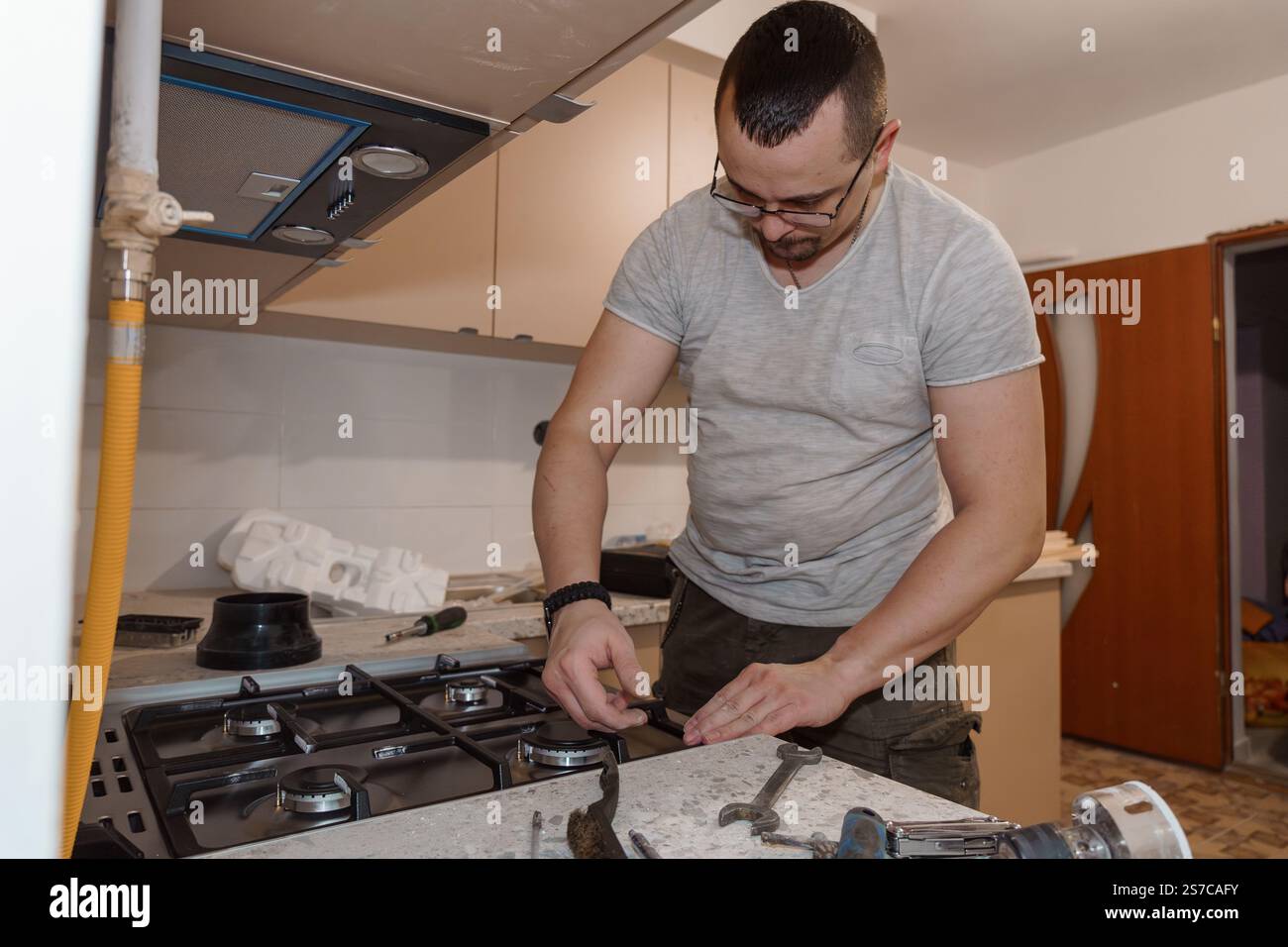 A Skilled Handyman Installing a Gas Stove in a Modern Kitchen. Stock Photo