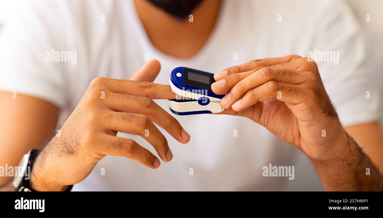 Unrecognizable man using pulse oximeter at home Stock Photo