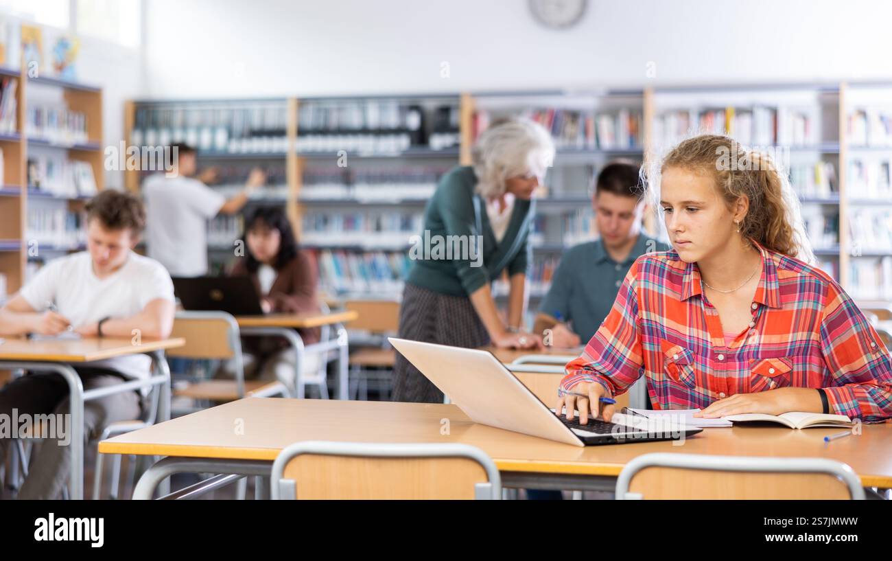 Teenager girl with a laptop studying in school library Stock Photo - Alamy