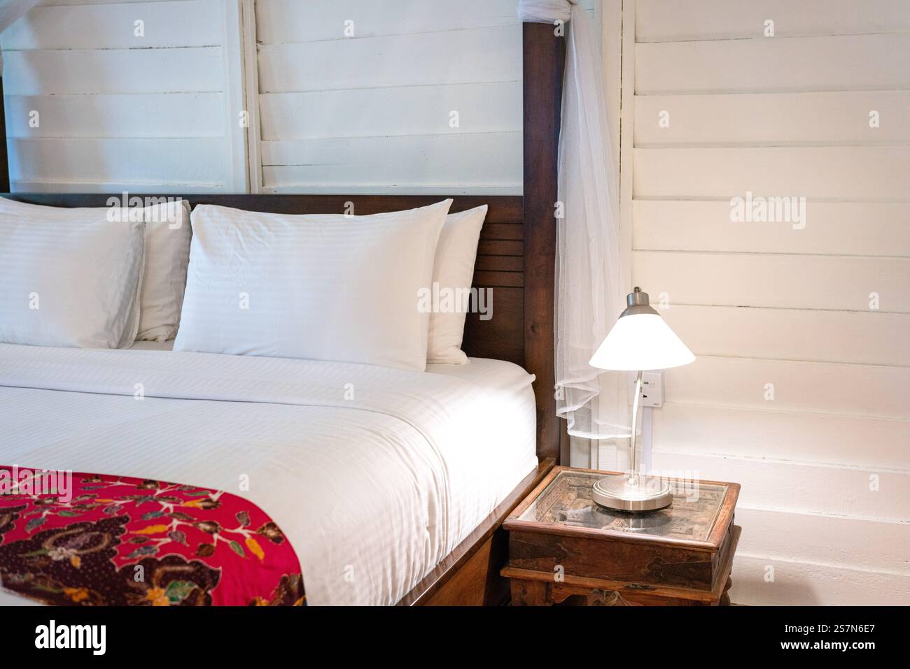 Bedside with side table and lamp on top of it. Cosy living. Stock Photo