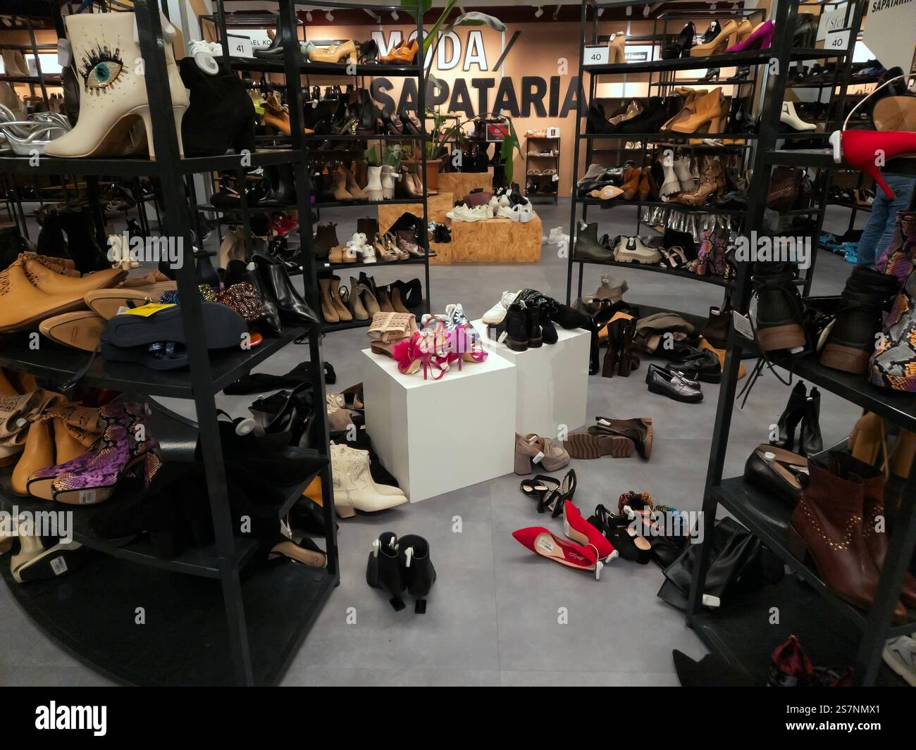 Women's shoe shop on sale, lots of boots and high heels untidy on shelves and on the floor - Smartphone Captured Stock Image