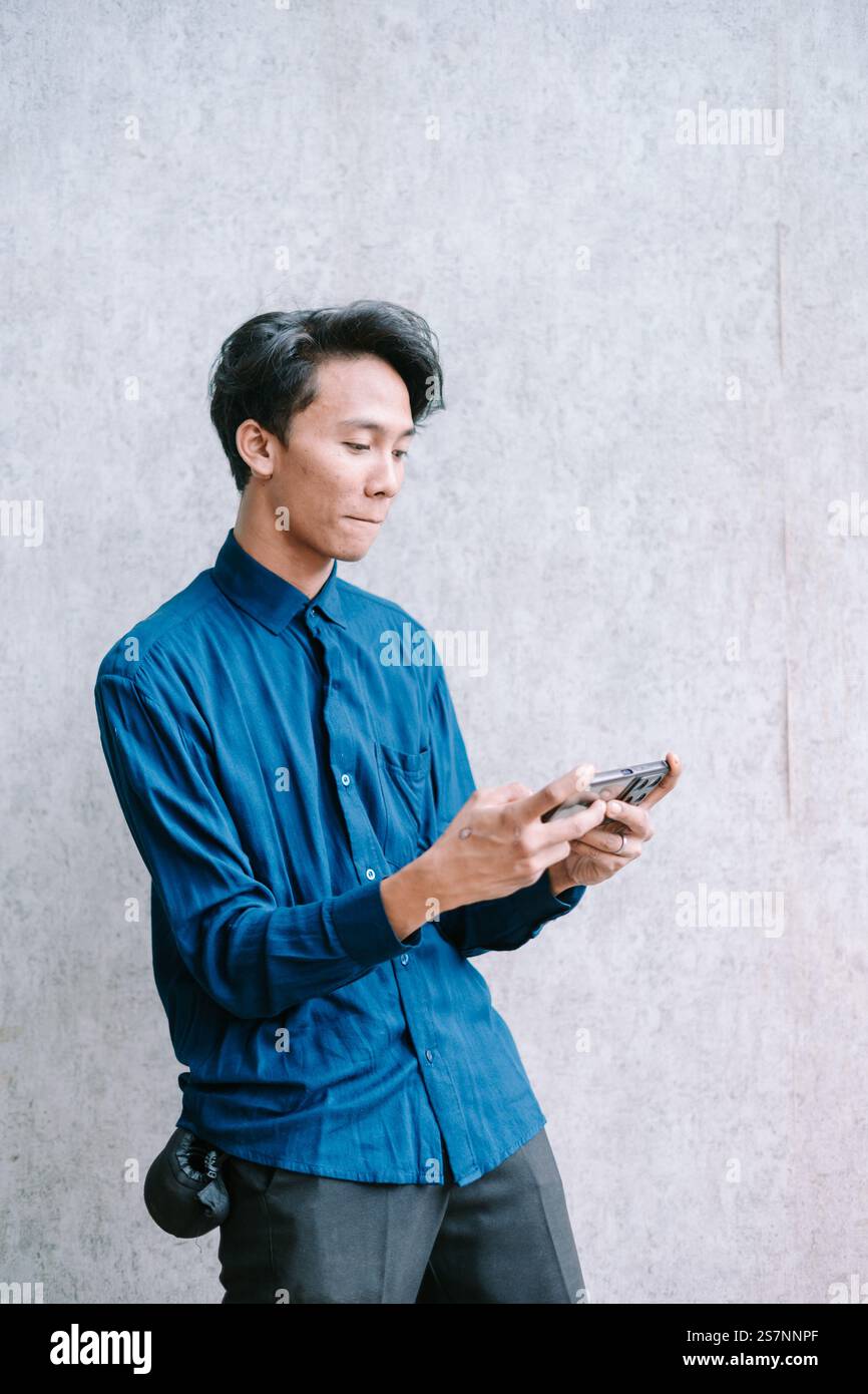 Young man engrossed in playing a mobile game, focused expression. Stock Photo