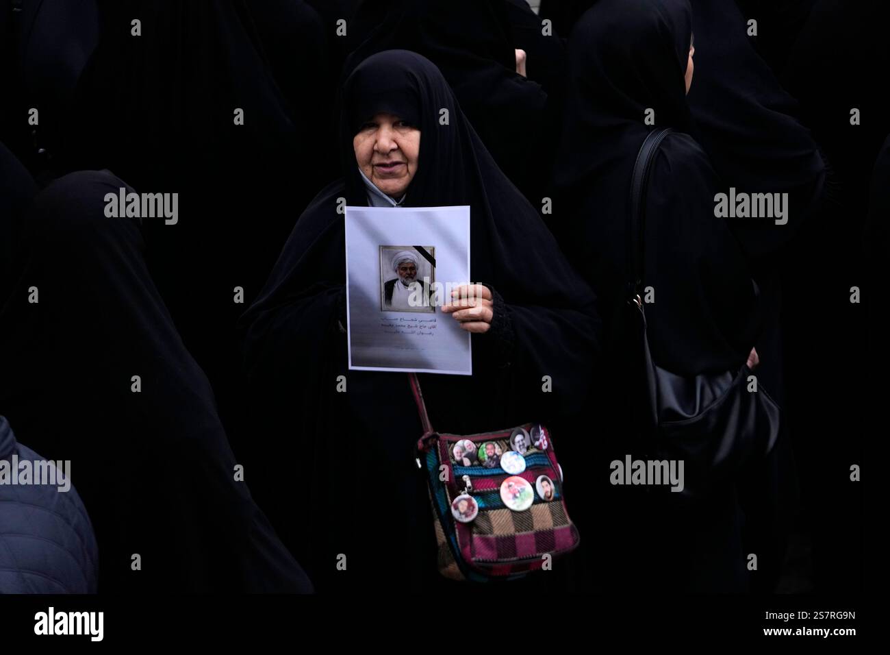A woman holds a poster of cleric Mohammad Mogheiseh, a judge of Iran's ...