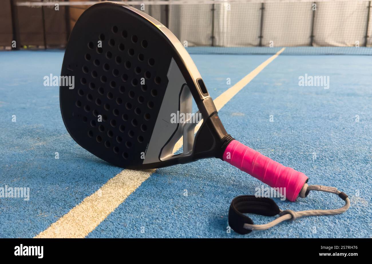 Photo of an orange padel racket and a ball on the ground of a blue ...