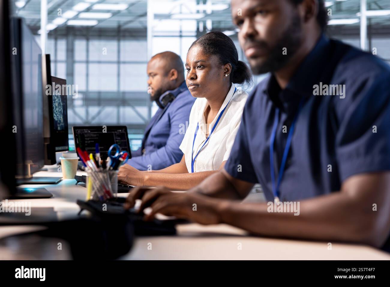 Team of data center engineers creating technical documentation for software applications. African american computer scientists working in server hub, maintaining databases Stock Photo