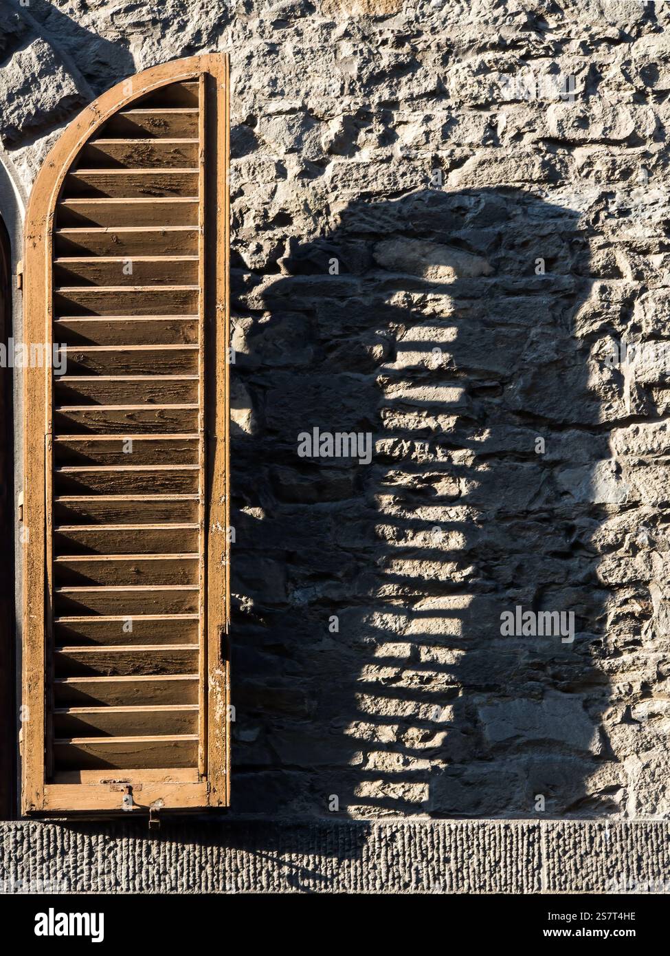 Wooden shutter with shadow on stone wall Stock Photo - Alamy