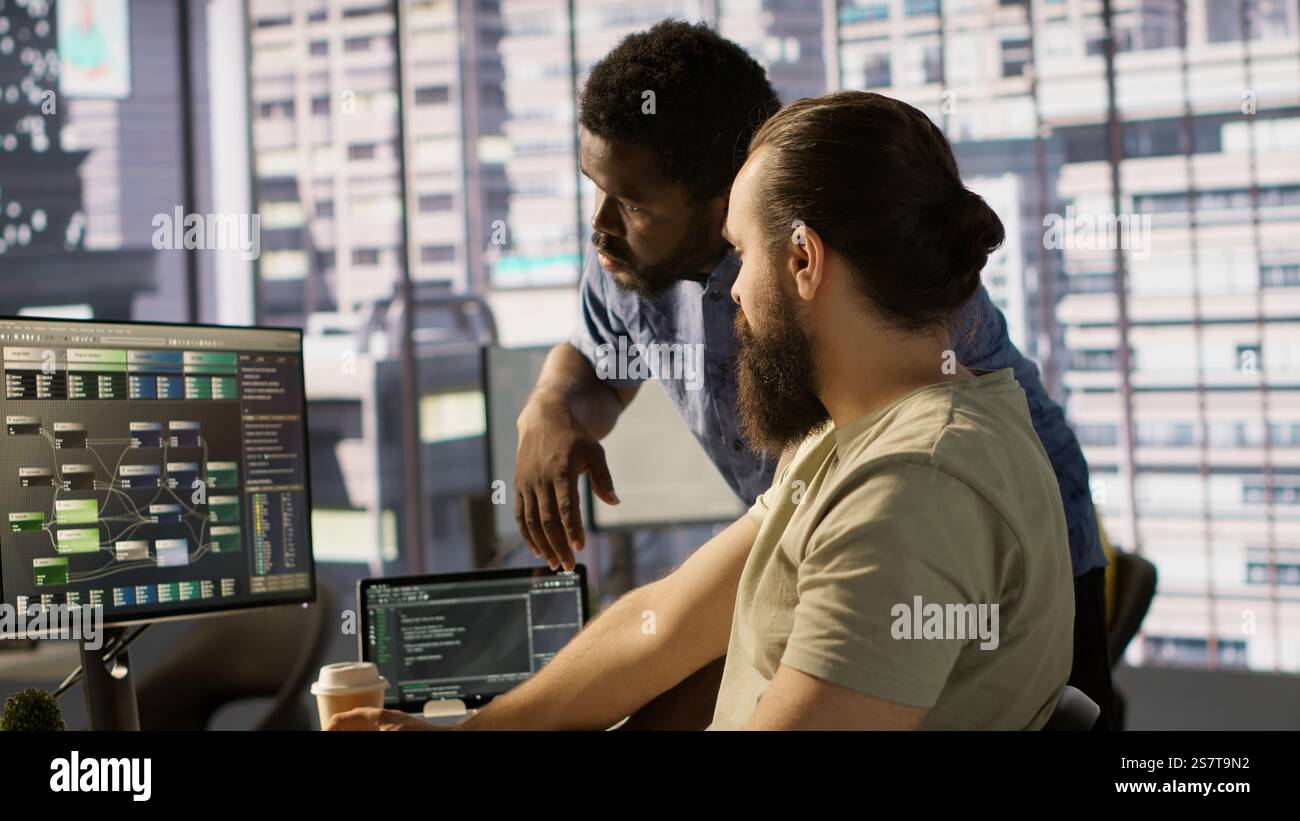 Manager correcting programmer mistakes while conducting code review to fix errors, identifying technical issues with company software. Team leader supervising IT staff member optimizing code, camera A Stock Photo