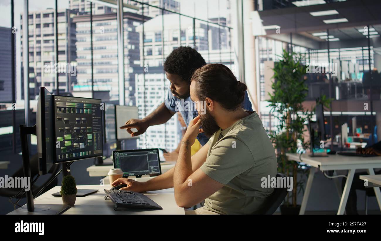 Manager correcting programmer mistakes while conducting code review to fix errors, identifying technical issues with company software. Team leader supervising IT staff member optimizing code, camera B Stock Photo