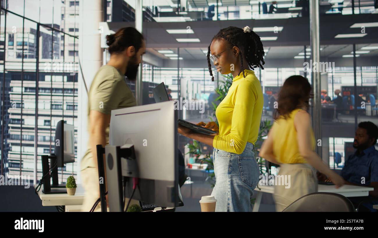 Computer scientist working, doing software debugging using notebook, troubleshooting errors. Woman standing in office, fixing coding issues using laptop, solving tasks, camera B Stock Photo