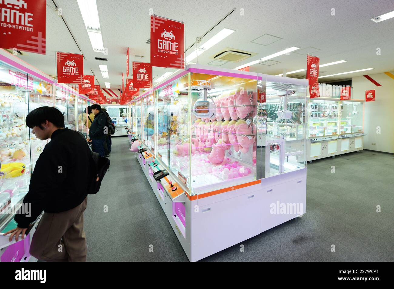 Japanese teenagers trying to pick toys in a toy crane claw machine ...